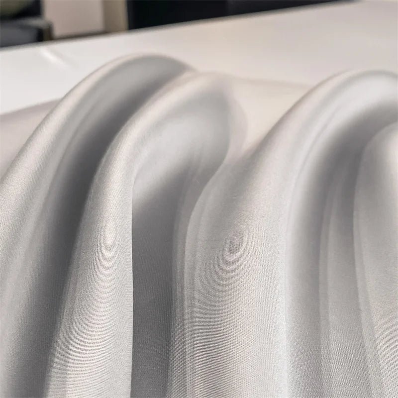 Detalle macro del tejido de bambú gris perla: pliegues y brillo satinado